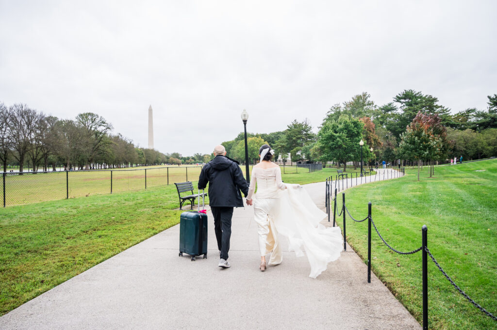 Bride and groom carrying a suitcase while strolling through Washington, D.C. on their wedding day.