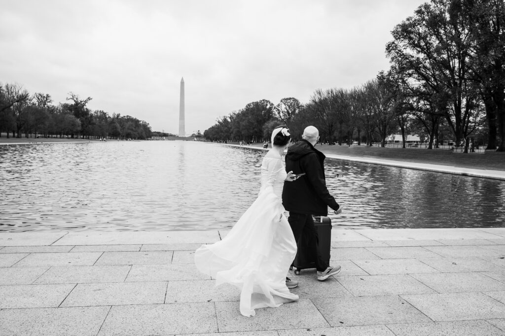 Couple strolling by the Reflecting Pool in wedding attire during their DC War Memorial wedding.
