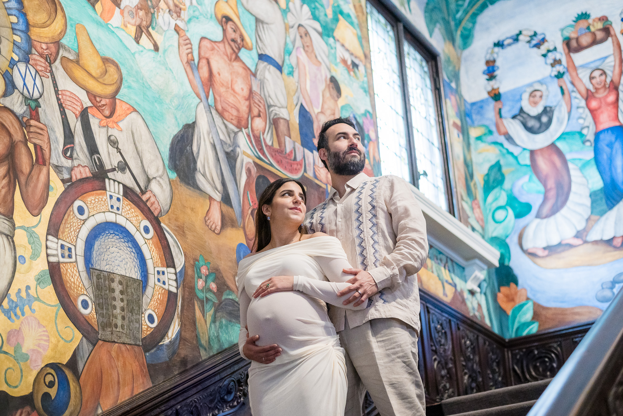 Expecting couple in front of the colorful architecture at the Mexican Cultural Institute.