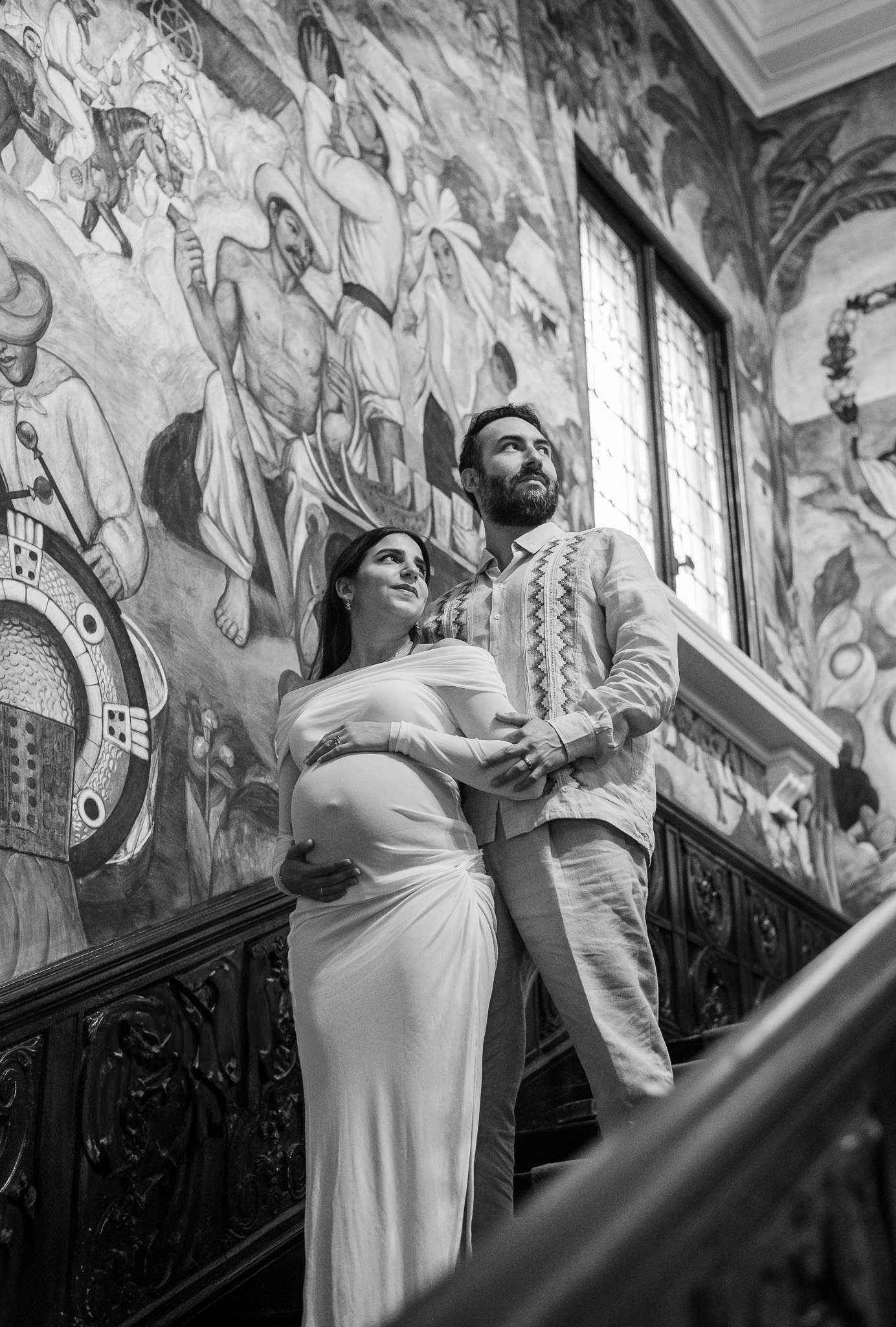 Couple in front of a mural on a staircase during a maternity session at the Mexican Cultural Institute.